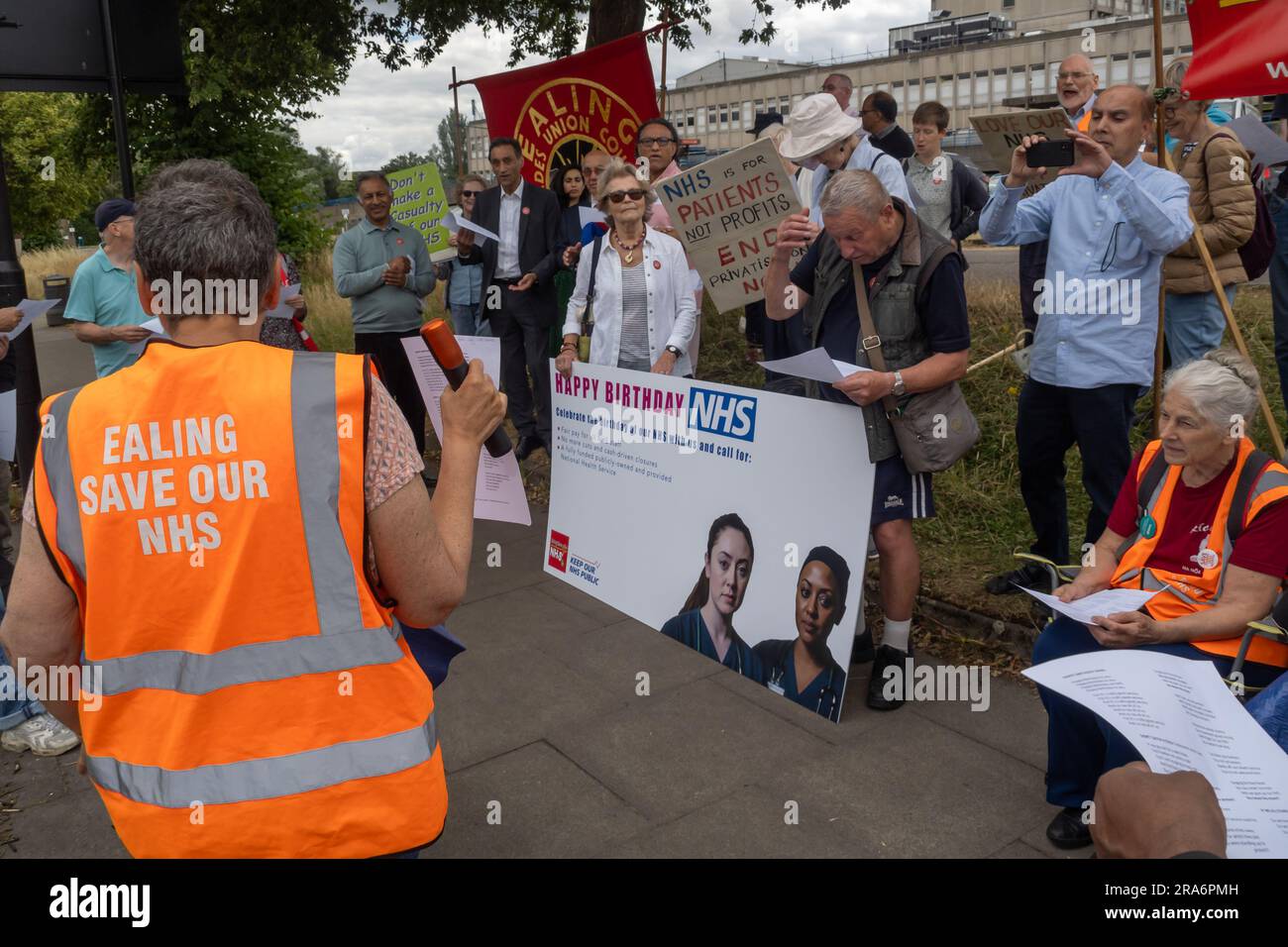 London, UK. 1 July 2023. Eve Turner, Ealing Save Our NHS, leads some singing. Campaigners from Ealing Save Our NHS celebrated 75 years of the NHS on the side of the main road in front of Ealing Hospital. Speakers called for a proper workforce plan, pointing out the failure of the recent government plan to recognise the realities of an overworked and underpaid system which has been deliberately run into the ground as a pretext for privatisation. Peter Marshall/Alamy Live News Stock Photo
