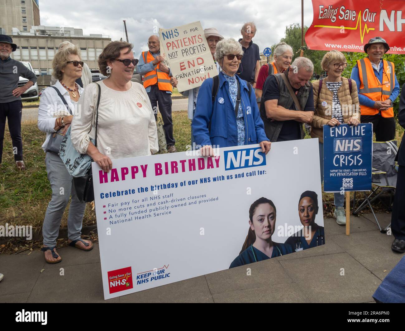 London, UK. 1 July 2023. Campaigners from Ealing Save Our NHS celebrated 75 years of the NHS on the side of the main road in front of Ealing Hospital. Speakers called for a proper workforce plan, pointing out the failure of the recent government plan to recognise the realities of an overworked and underpaid system which has been deliberately run into the ground as a pretext for privatisation. Peter Marshall/Alamy Live News Stock Photo