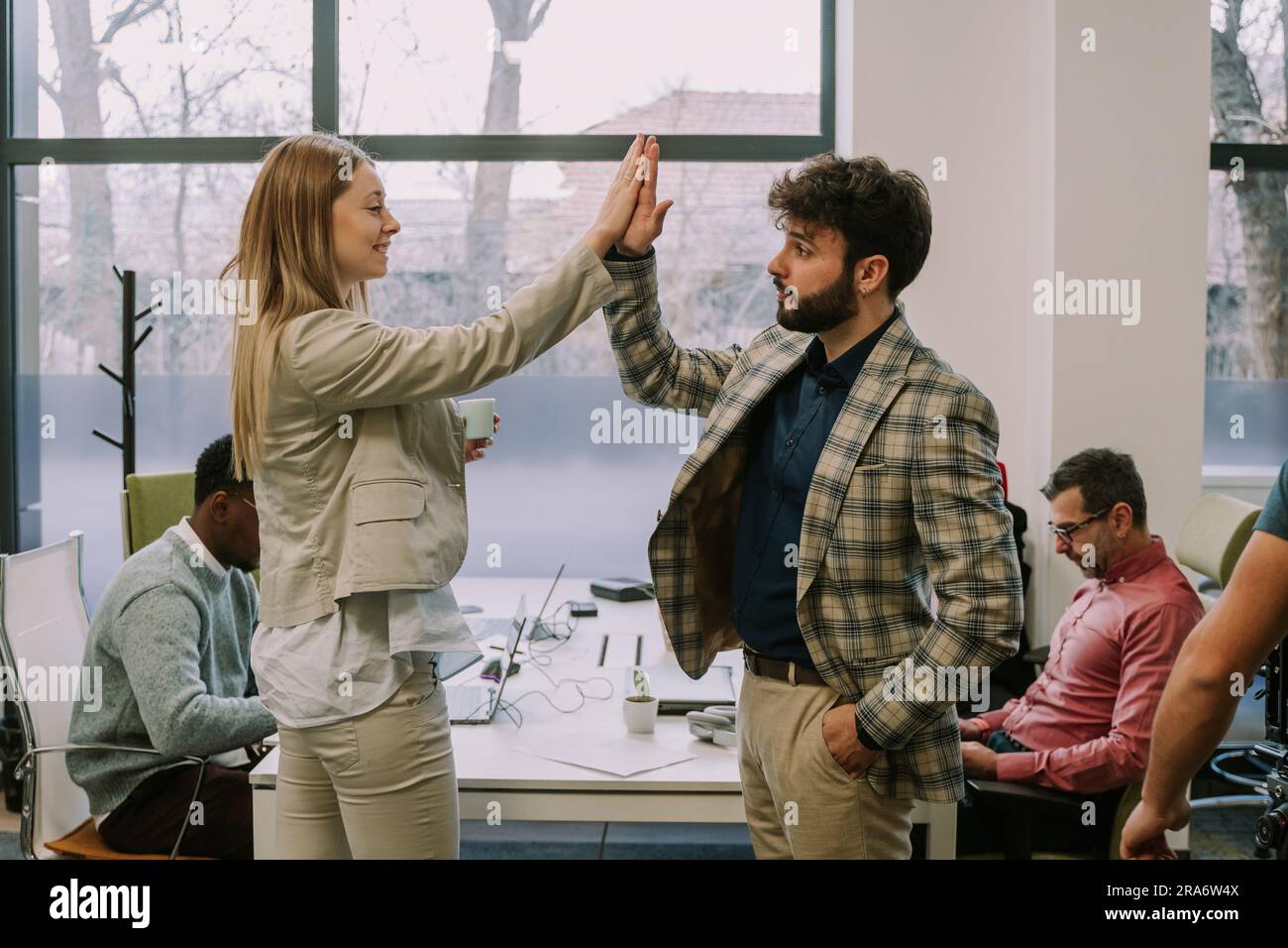 Two office colleagues doing a high five after agreeing on something at the office Stock Photo