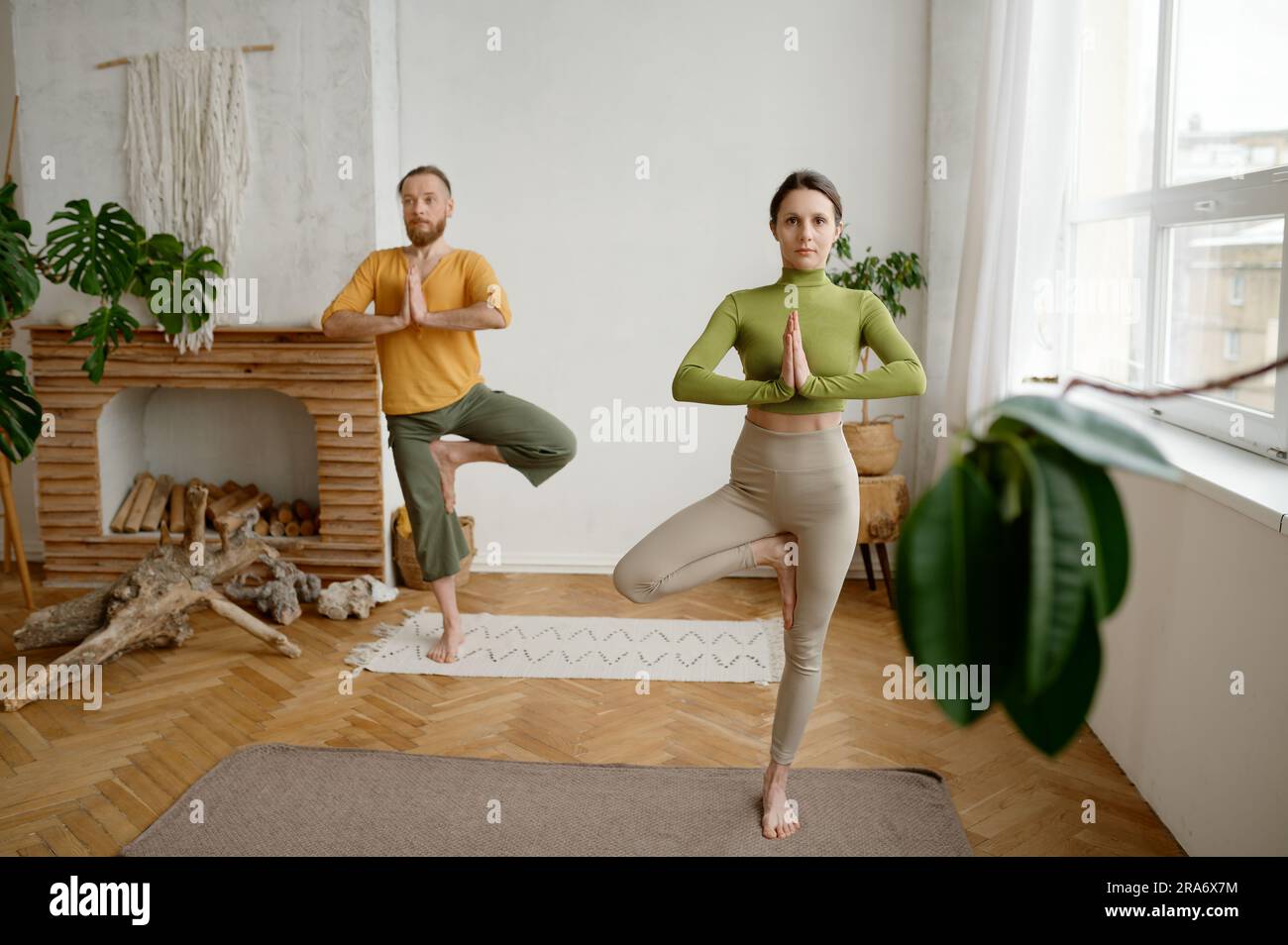 Couple standing in yoga vrikshasana tree pose, cropped shot with selective focus Stock Photo