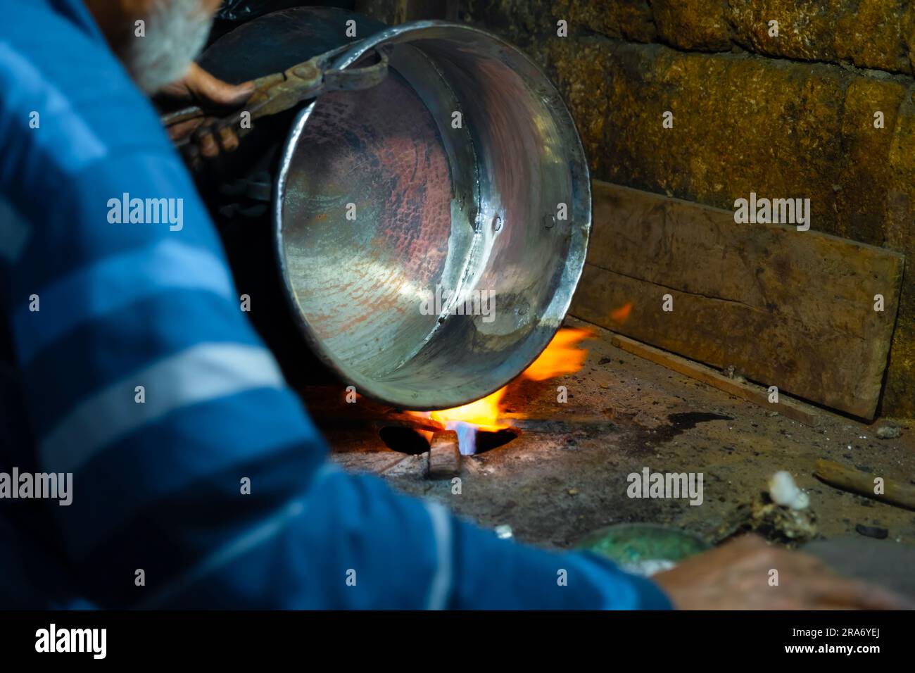 Cropped image of the traditional Turkish tinsmith covering the copper object with tin over fire. Stock Photo