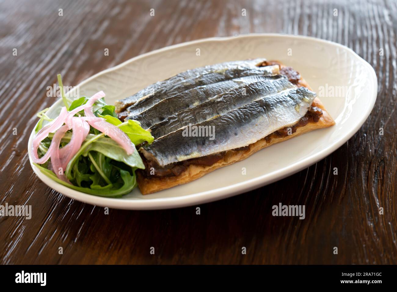 Studio photo of a plate of sardines on toast with salad, gourmet style