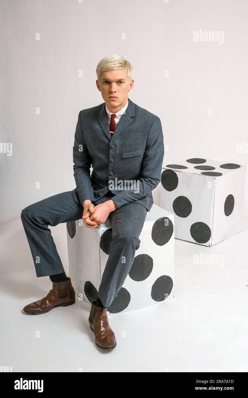 Young man with suit sitting on a giant dice . Stock Photo