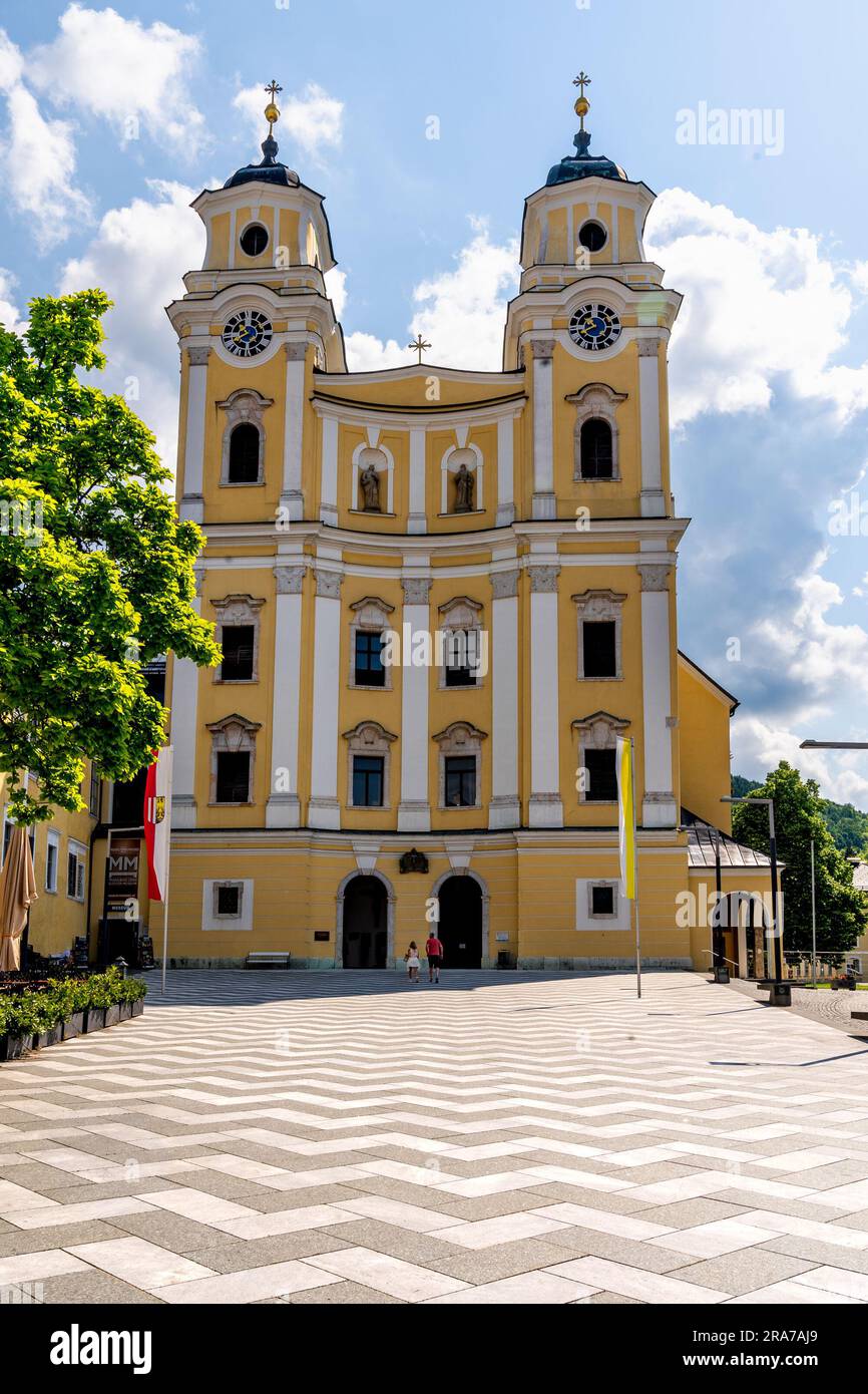 Mondsee, Upper Austria – AT – June 7, 2023 Exterior view of the yellow baroque façaded parish church, Basilica of Saint Michael, a former monastery. Stock Photo