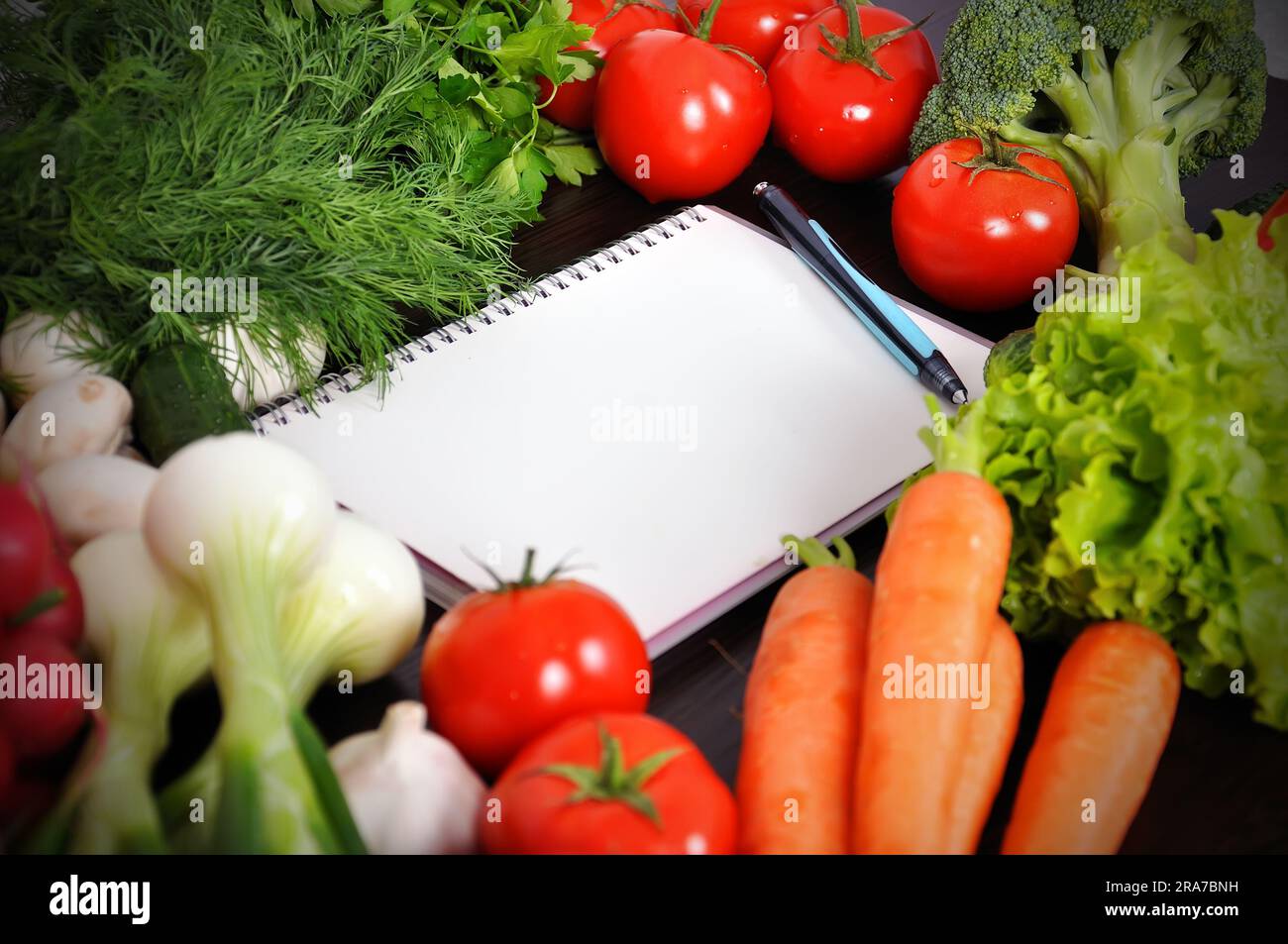 recipe book with vegetables and herbs on wooden table Stock Photo