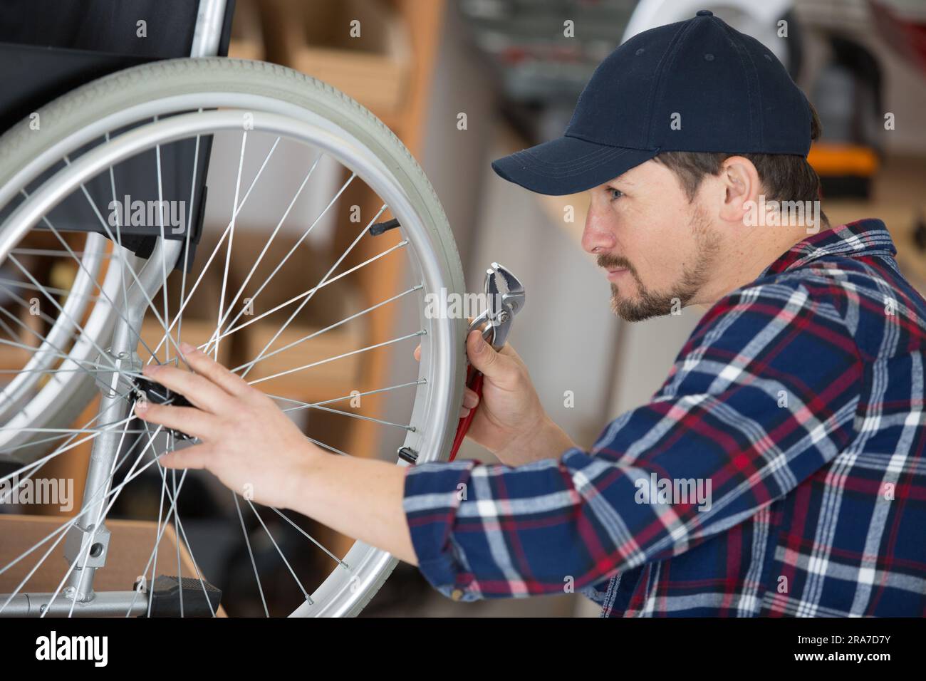 mechanic checking the spokes on a wheelchair Stock Photo