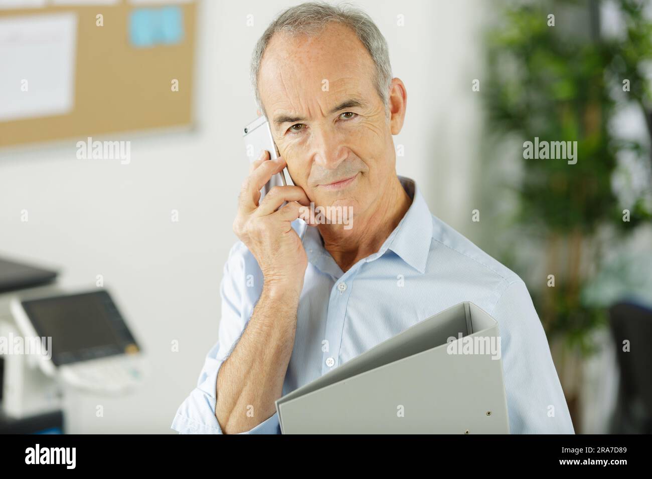 senior businessman holding folder and talking on telephone Stock Photo.
