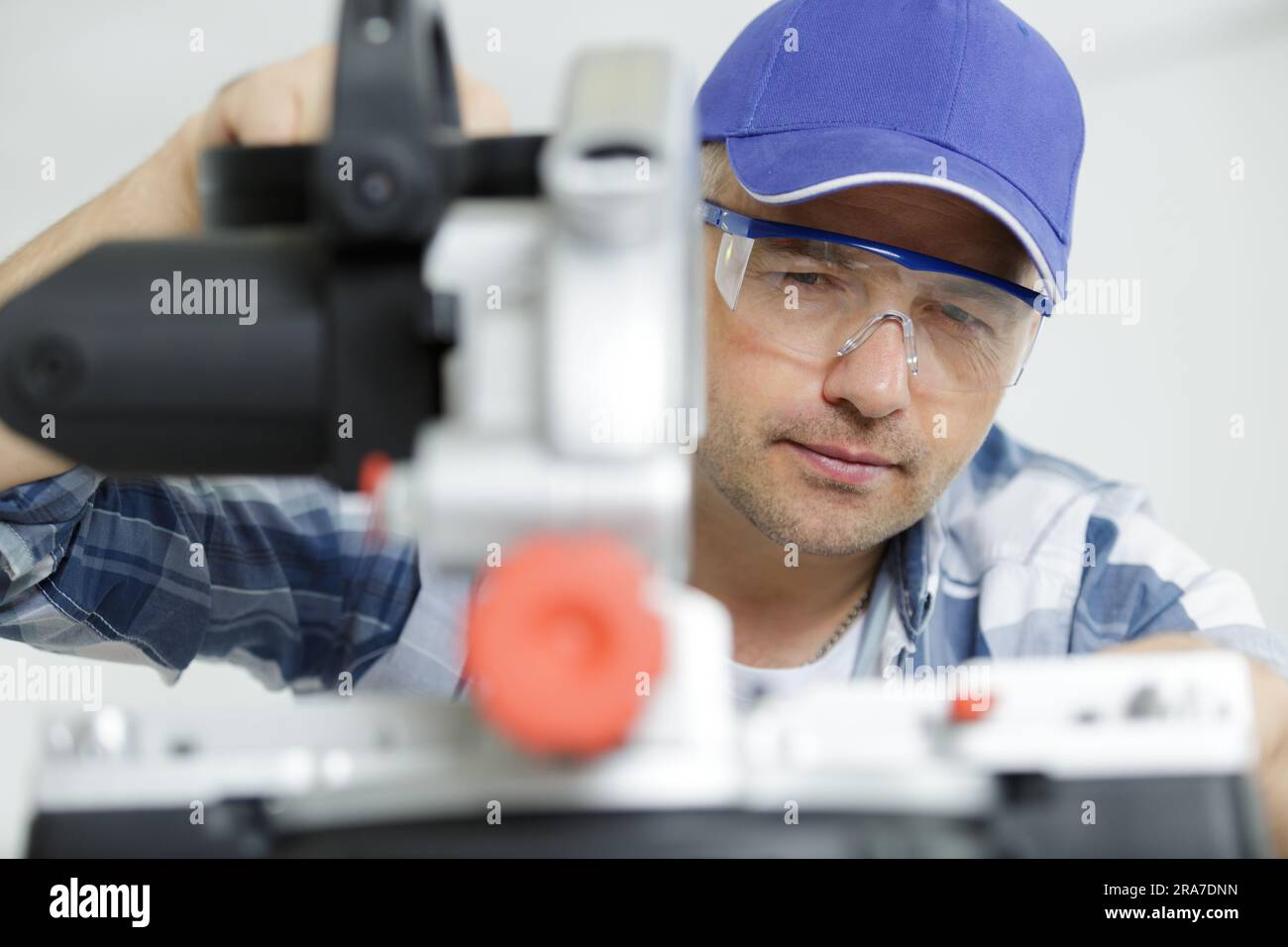 worker holds the miter saw and a piece of plywood Stock Photo Alamy