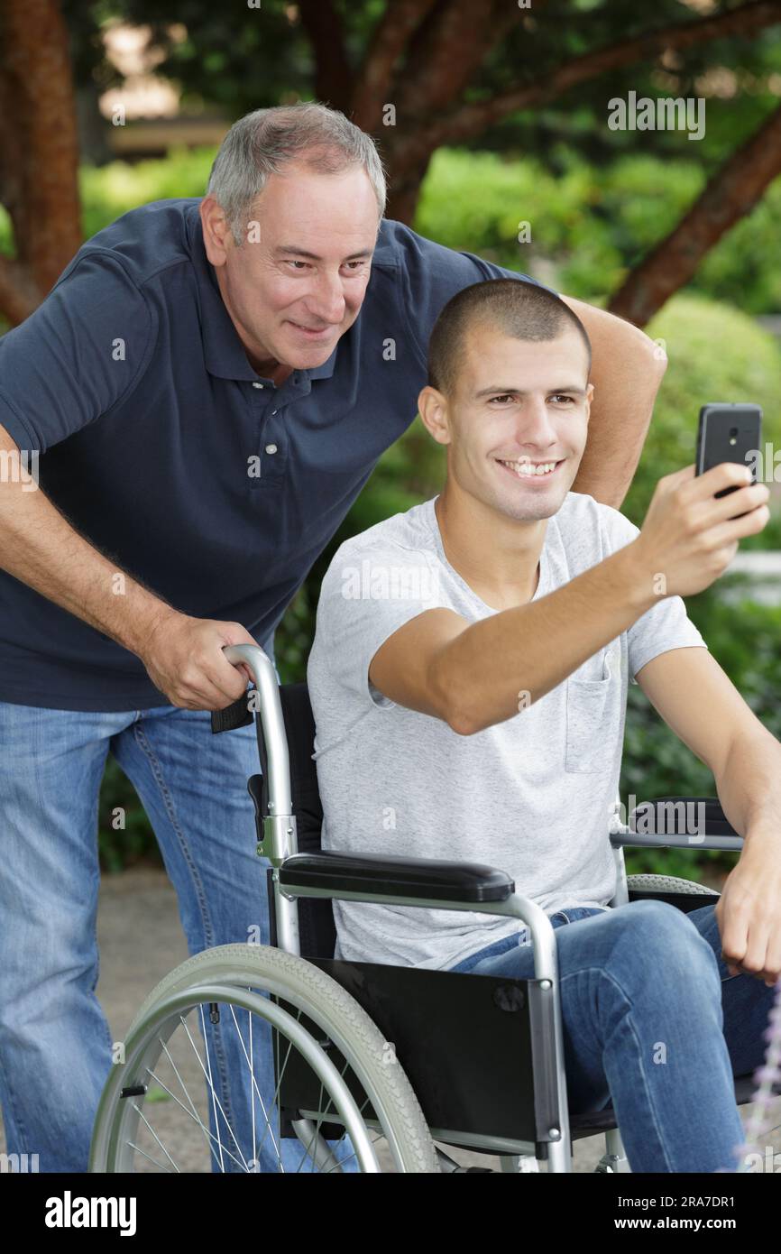 young man in wheelchair taking selfie with father Stock Photo - Alamy