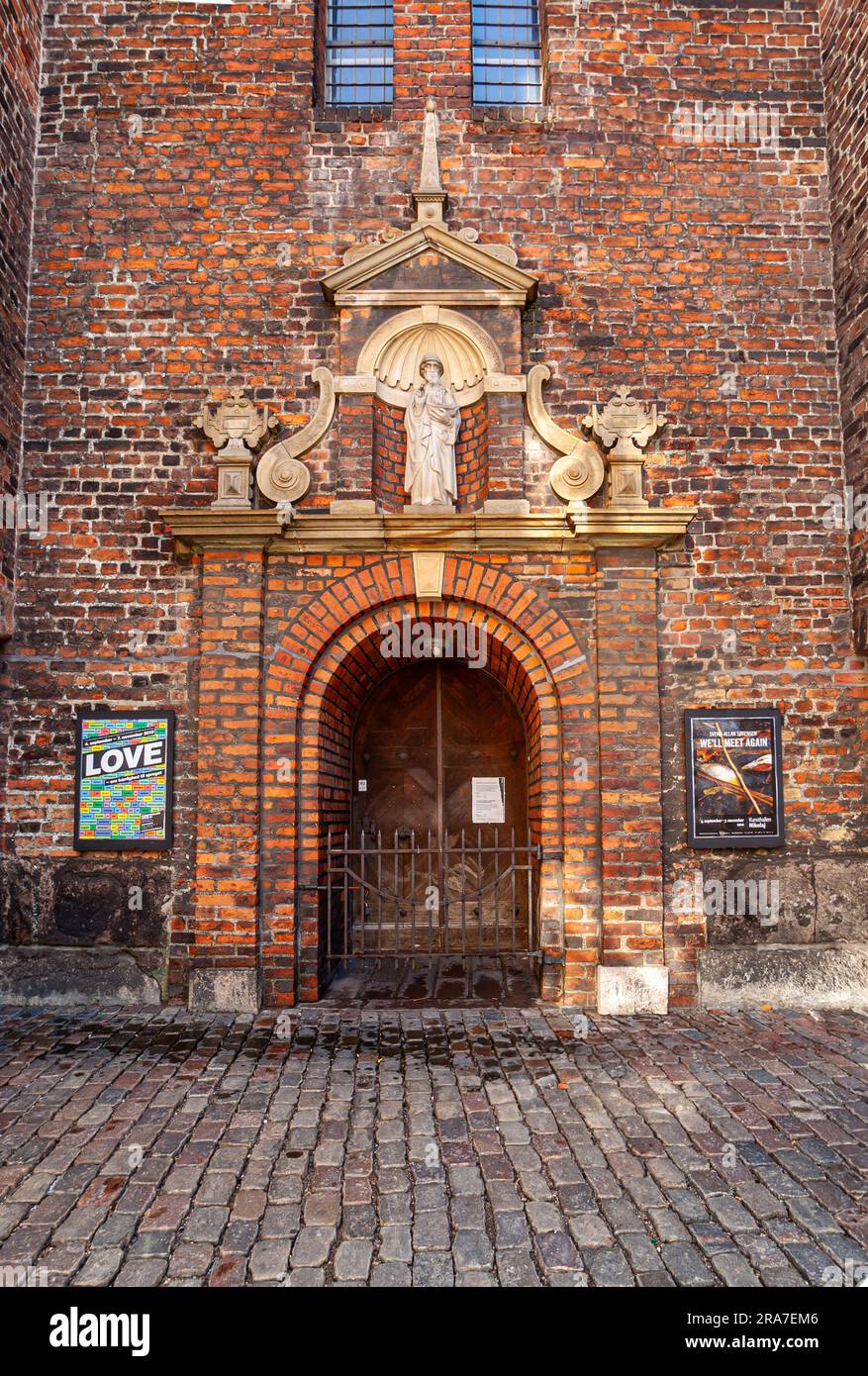 Copenhagen, Denmark - September 15, 2010: Nikolaj Kunsthallen, formerly the Nicholas church, red brick baroque wall with saint statue on top of histor Stock Photo
