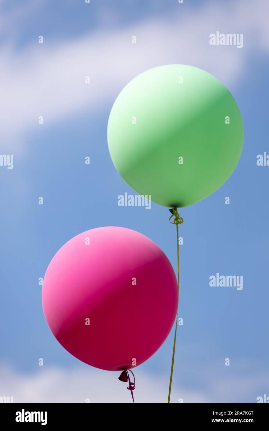 helium inflated green and red balloons flying in the blue sky with