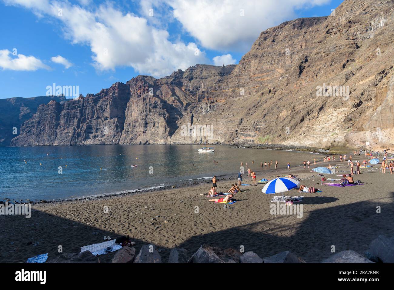 Los Gigantes, Tenerife, Canary Islands, Spain - September 21, 2022: People relax on picturesque Los Guios beach amongst the majestic cliffs Stock Photo