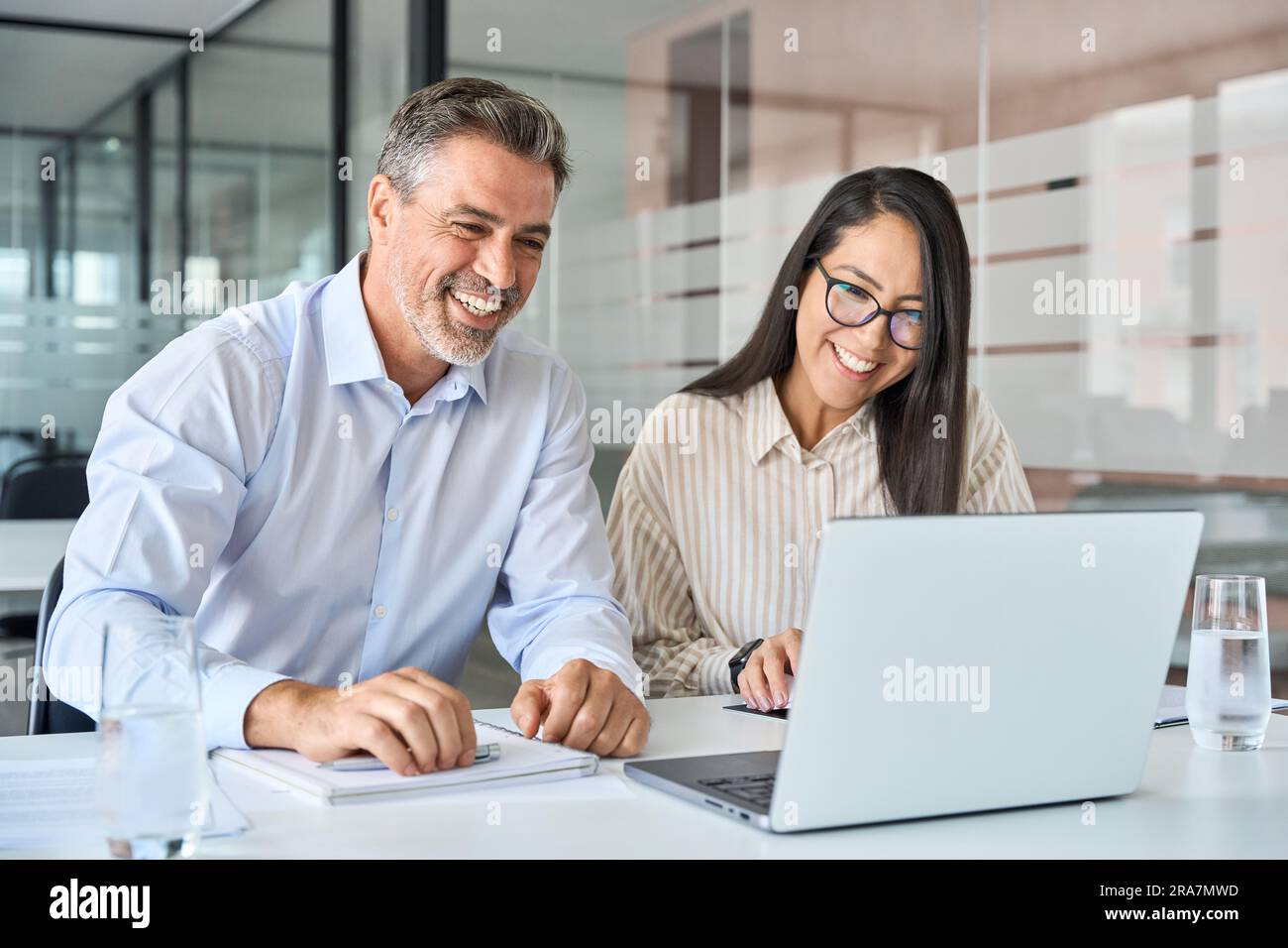 Happy diverse executives team two professional managers looking at laptop. Stock Photo