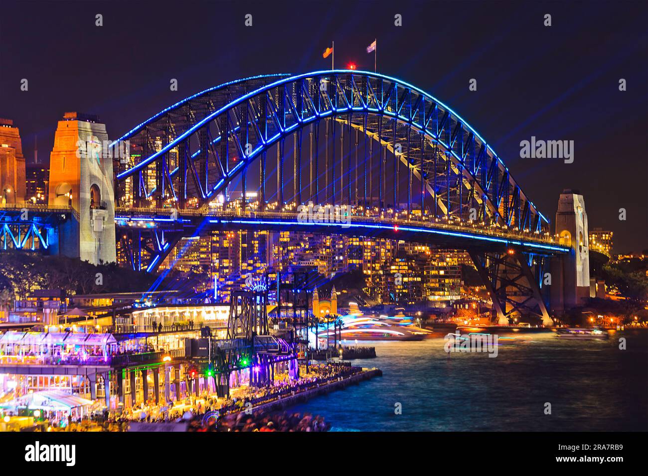 Arch of Sydney Harbour bridge with bright illumination over harbour waters at Vivid Sydney in Australia at night. Stock Photo