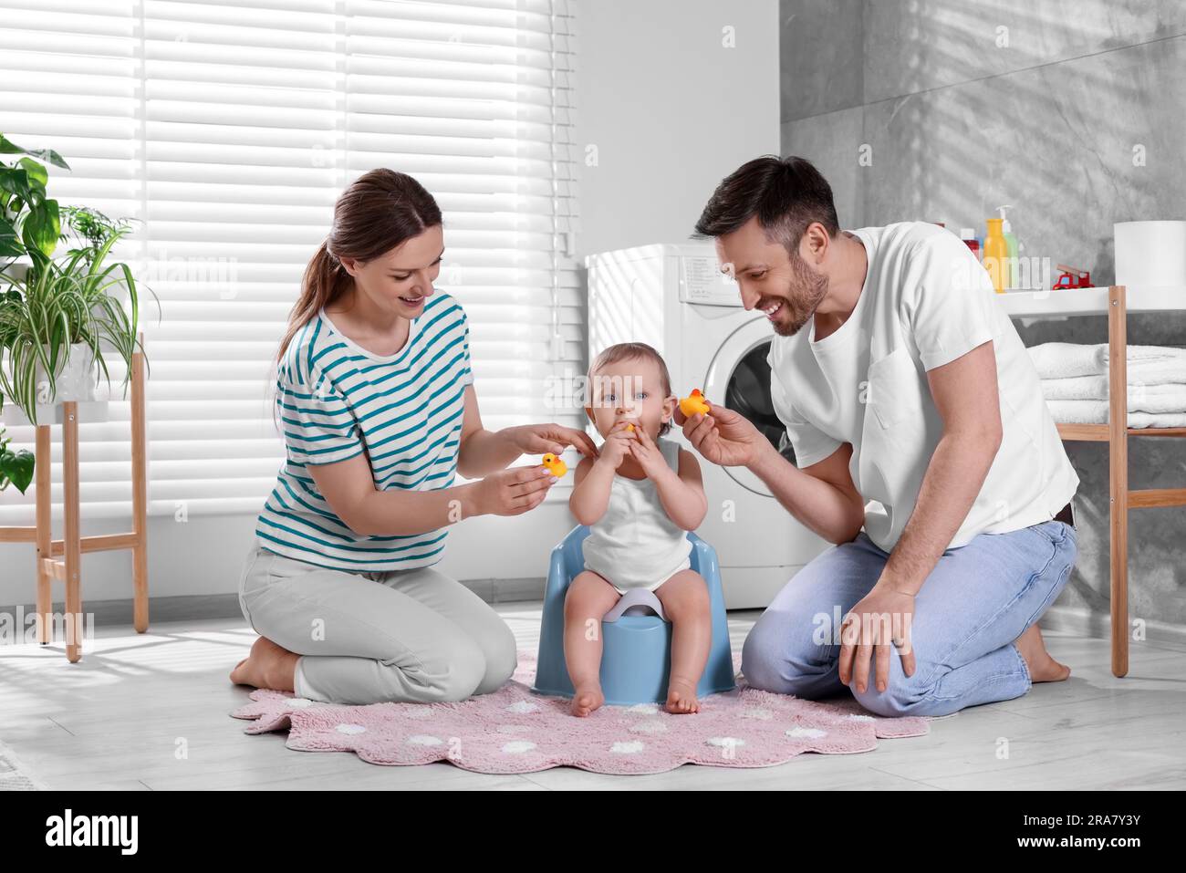 Parents training their child to sit on baby potty indoors Stock Photo Alamy