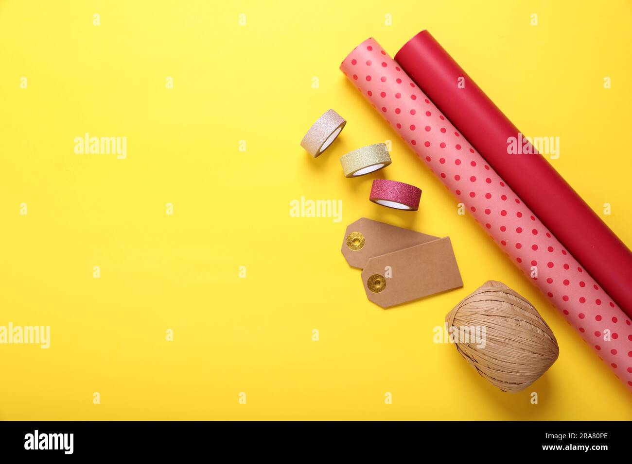 Rolls of colorful wrapping papers, ribbons and tags on yellow ...