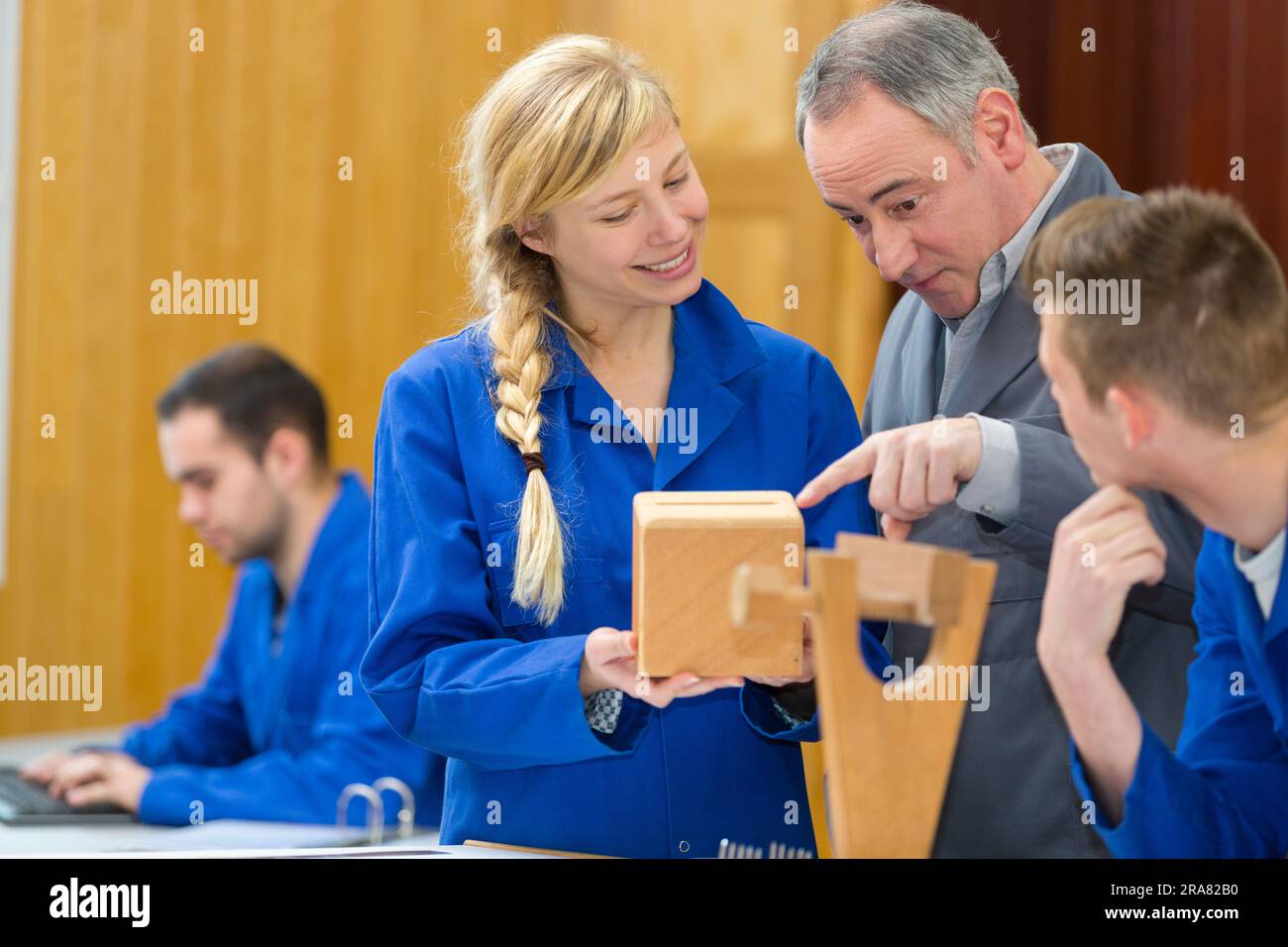 teacher helping a students in a woodwork class Stock Photo