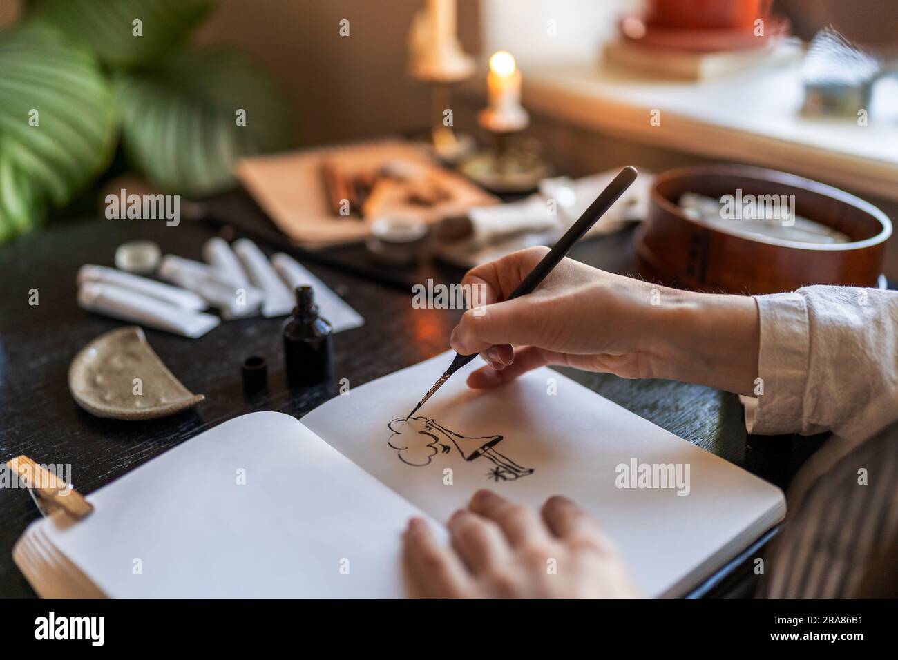 Artist holding fountain pen drawing with ink, creating artwork Stock