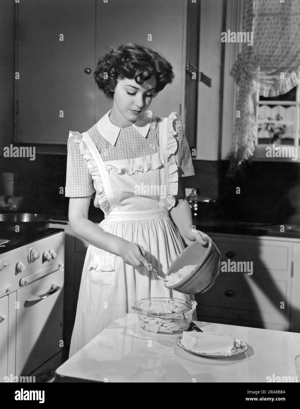 Hollywood, California:  1942. Actress Marsha Hunt prepares apple cobbler in her kitchen. She was blacklisted during the 1940's and 50's for her First Amendment stands. Stock Photo