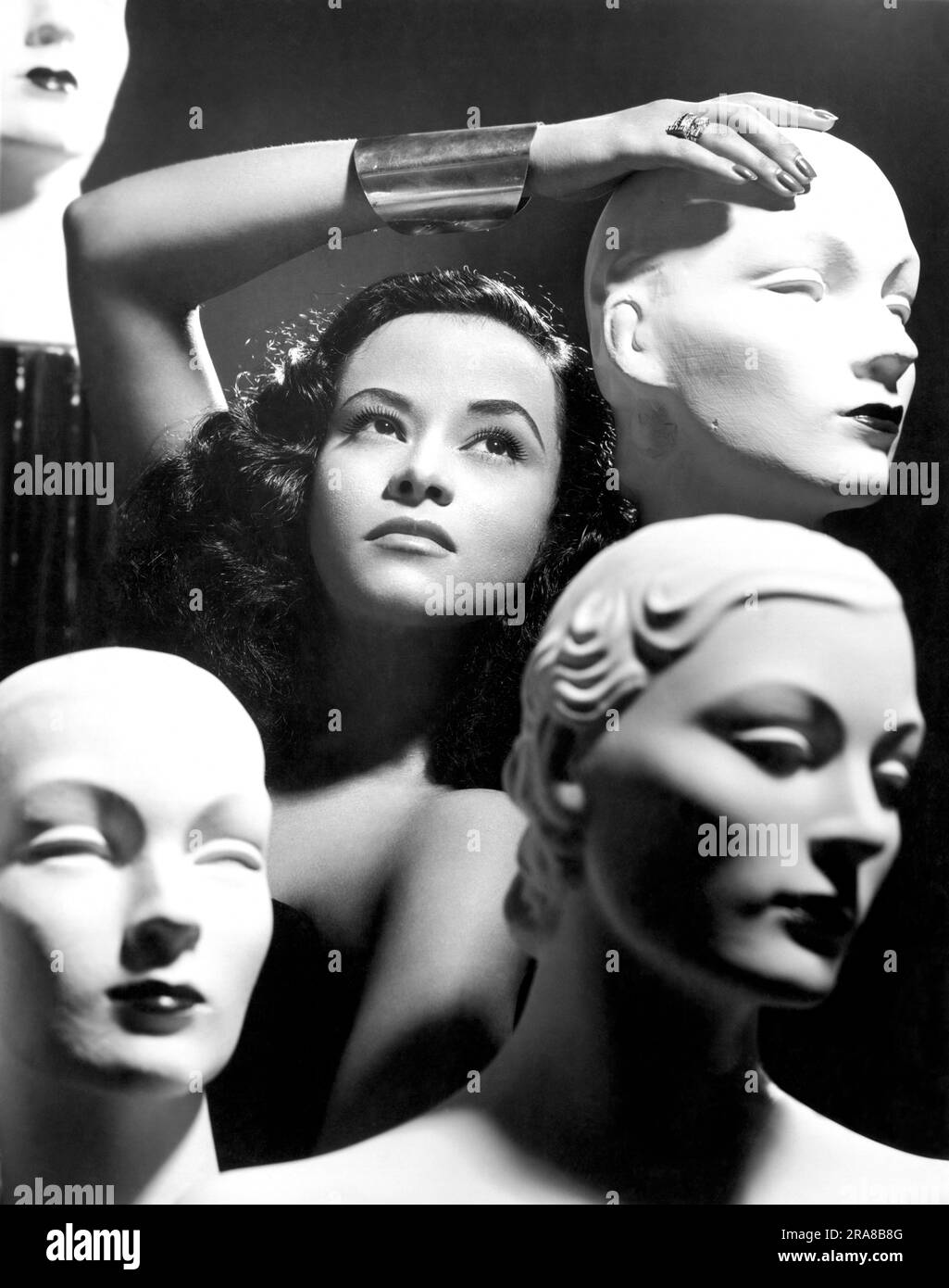 United States:  1952 A woman poses with mannequin heads in a promotional photograph for the 'Sans-Souci Revue'. Stock Photo