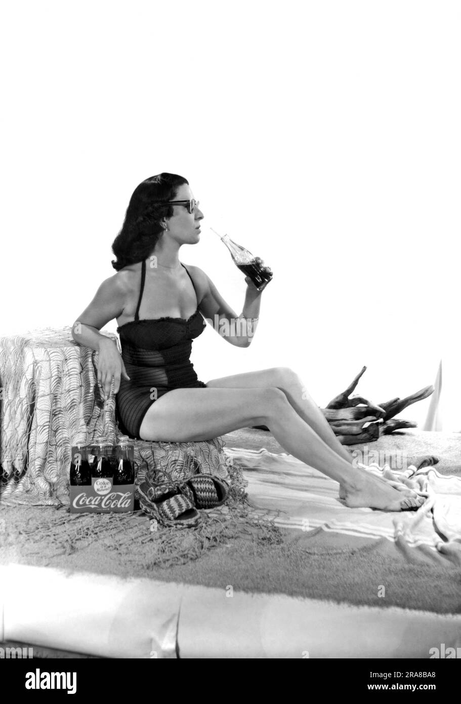 United States: c. 1947. A set for a photo shoot for a Coca Cola ad, complete with beach sand and a pretty woman in a bathing suit. Stock Photo