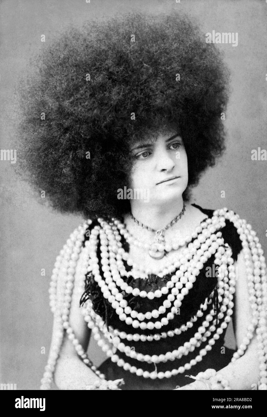 New York, New York:  c. 1880. A protrait of a woman vaudeville or circus performer with an immense afro hairdo and many rows of beads on her body Stock Photo