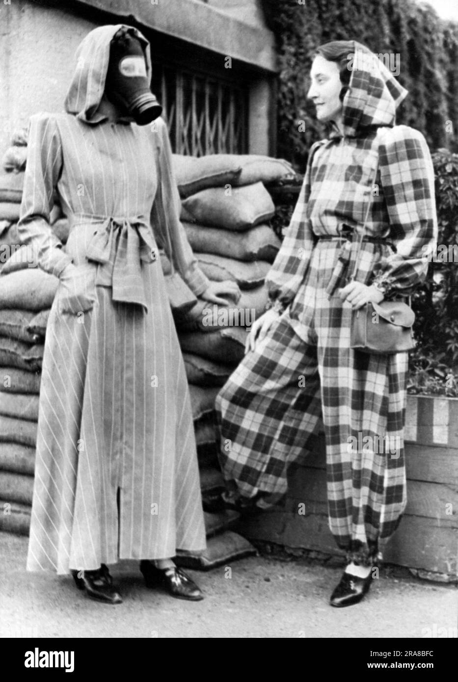 London, England:  Sept 14, 1939. The very latest fashion in air raid shelter wear is a slip on dressing gown complete with hood, and can be left open, (left), or zipped into trousers, (right). Stock Photo