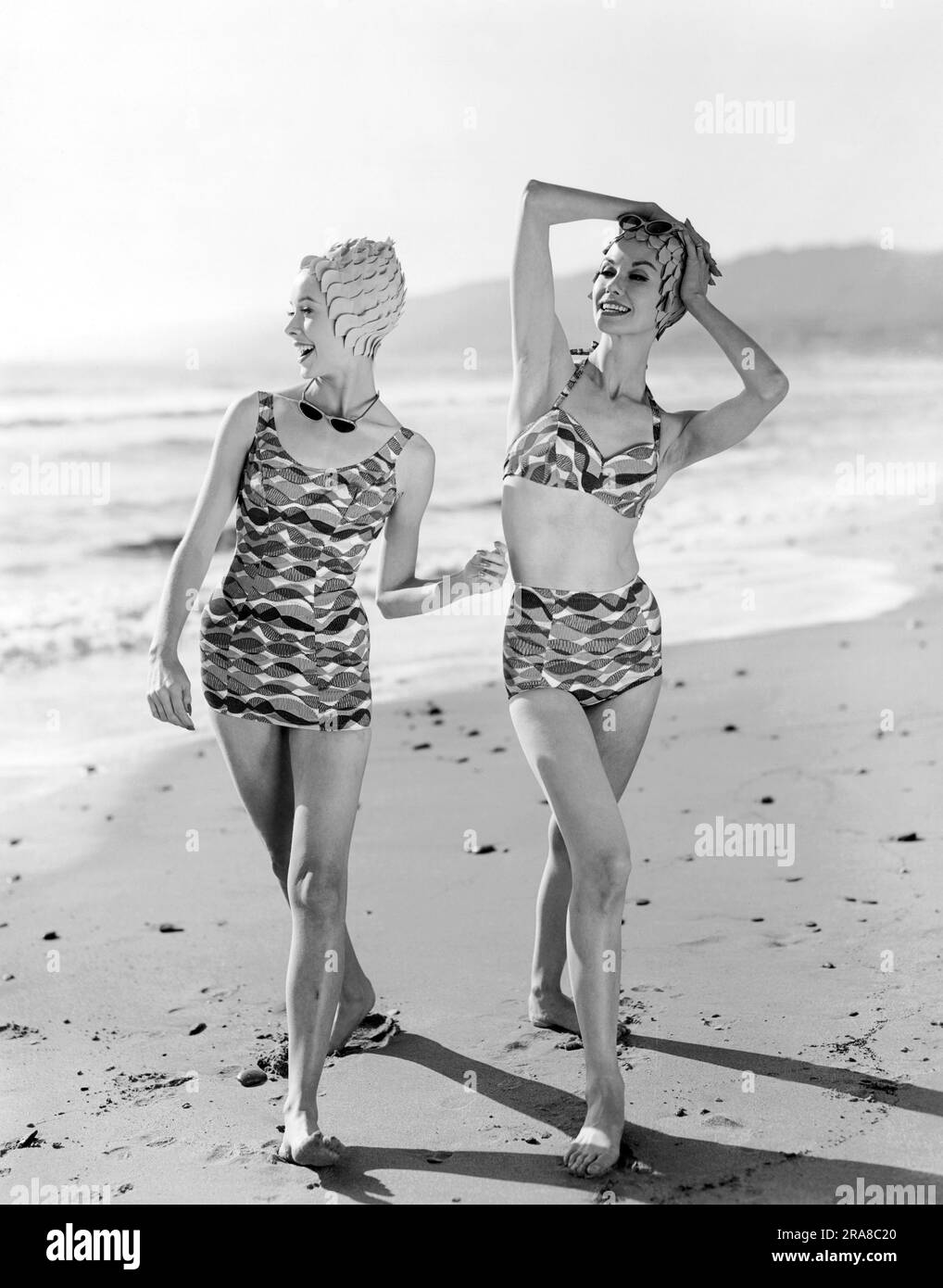 United States:   c. 1960   Looking ready to dive in, these beauties model the newest bathing fashions including swim caps and sleek sunglasses. Stock Photo
