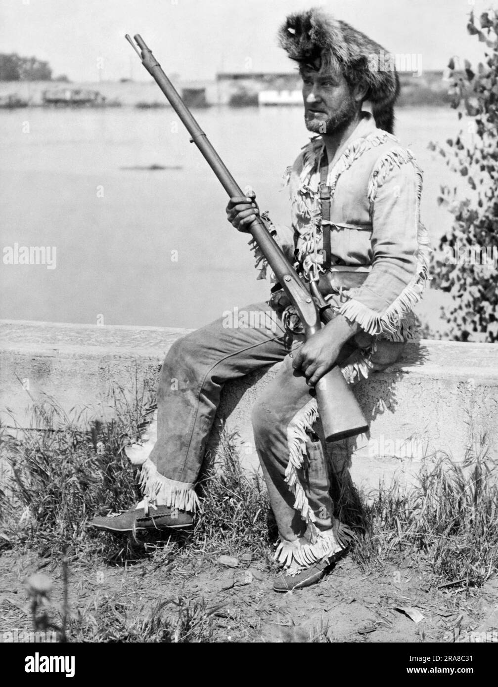 United States:  c. 1928 A man wearing a Davy Crockett outfit with a coonskin cap and a musket. Stock Photo