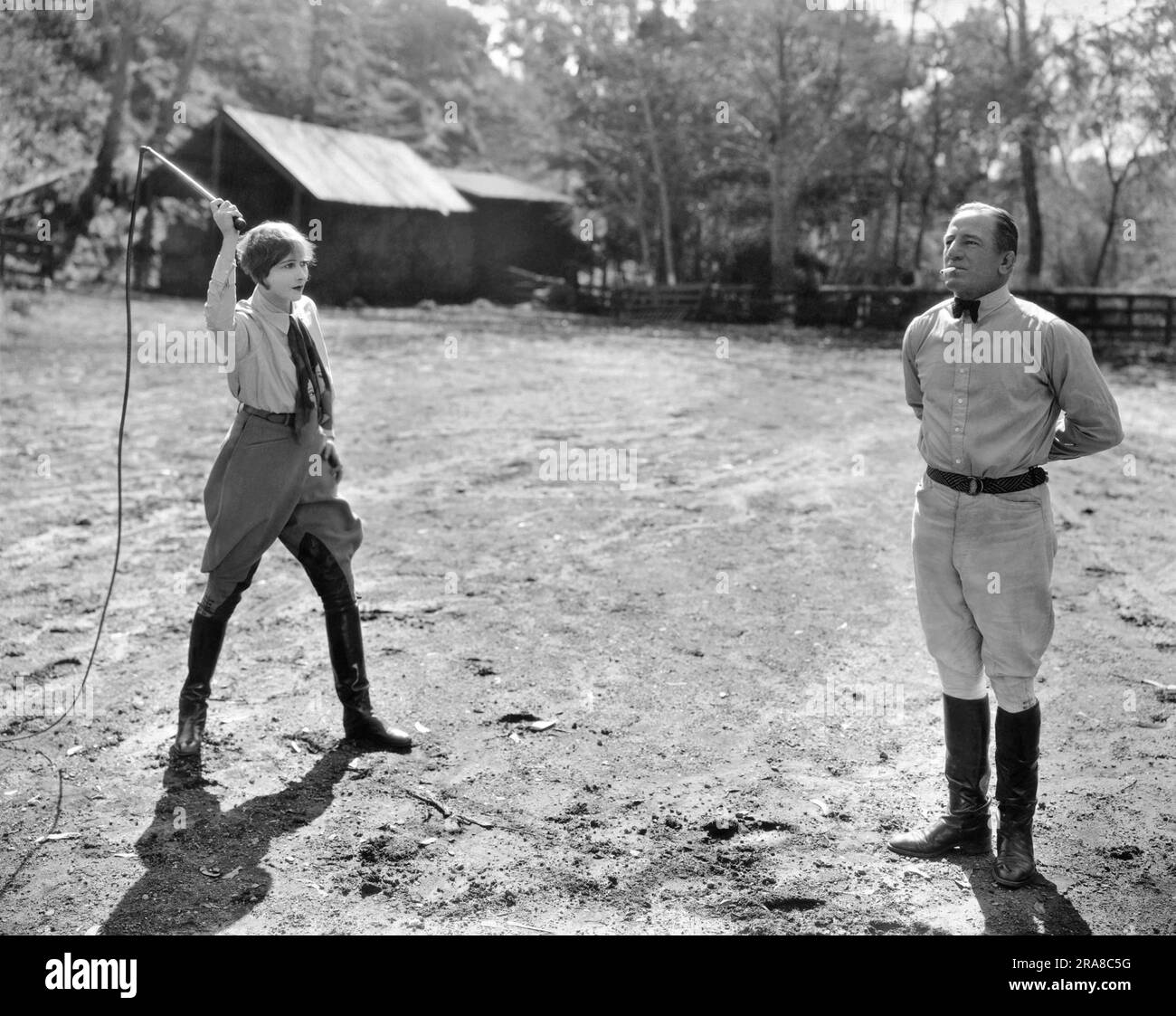 Hollywood, California:  March 16, 1925 Actress Anna Q. Nilsson prepares to knock a cigarette out of Australian star athlete Snowy Baker's mouth at fifteen feet feet with a bullwhip. Baker taught her the stunt and she is said to be the only woman in America that can do it. Stock Photo