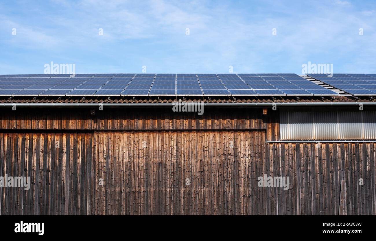 a wooden barn in the country with solar panels installed on the roof