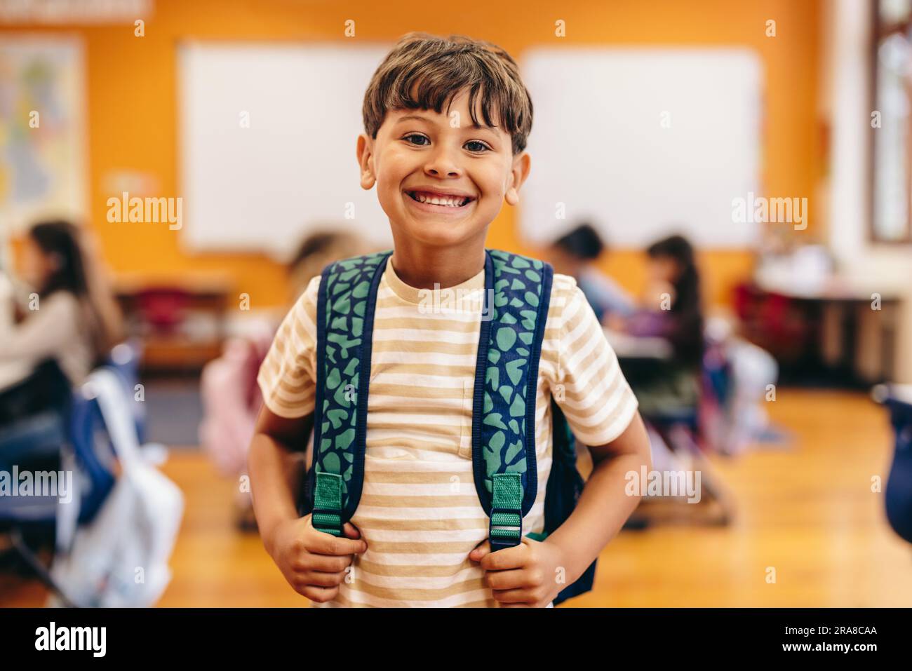 Lifestyle of learning: Elementary school child excited for first day of class. Little boy smiling at the camera as he stands in an elementary school c Stock Photo