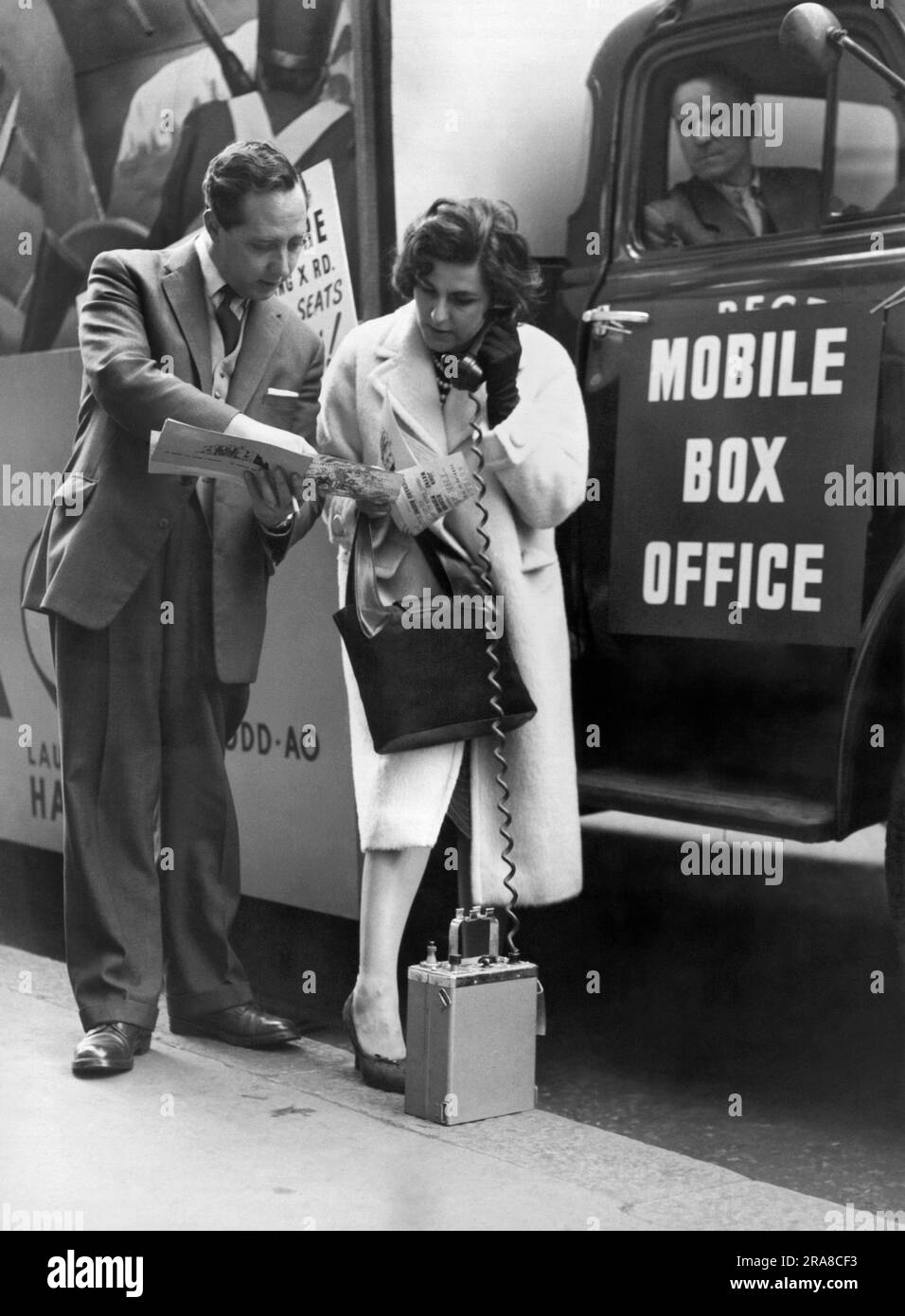 London, England:  October 17, 1960 A movie fan buys a ticket from the first mobile box office in London by ordering seats with a direct radio link to the cinema. The movie is the premier of 'The Alamo' with John Wayne. Stock Photo