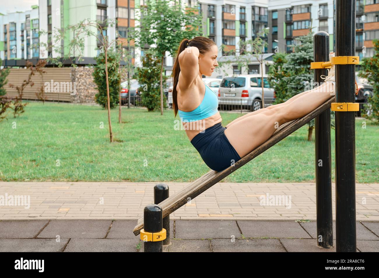 Active woman pumping her abs lying on the sports field of a residential ...