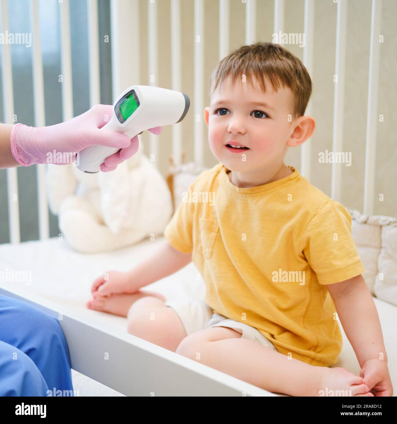 The doctor is using an electronic thermometer to measure the child's