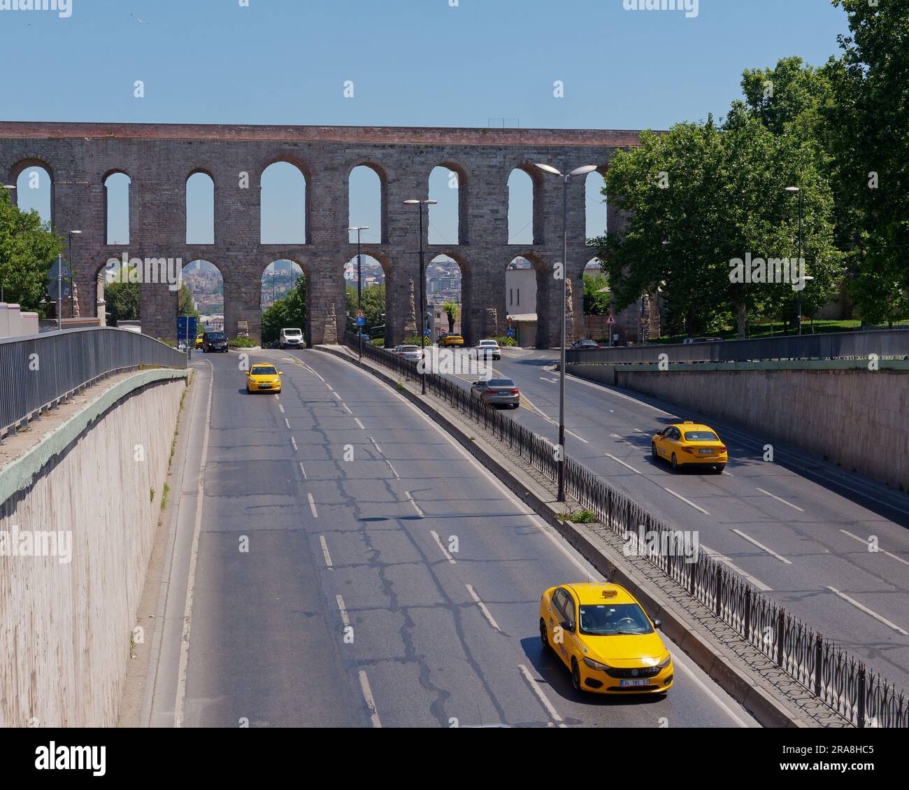 Yellow taxis on a road in front of the Aqueduct of Valens, a Roman Aqueduct in Istanbul, Turkey Stock Photo