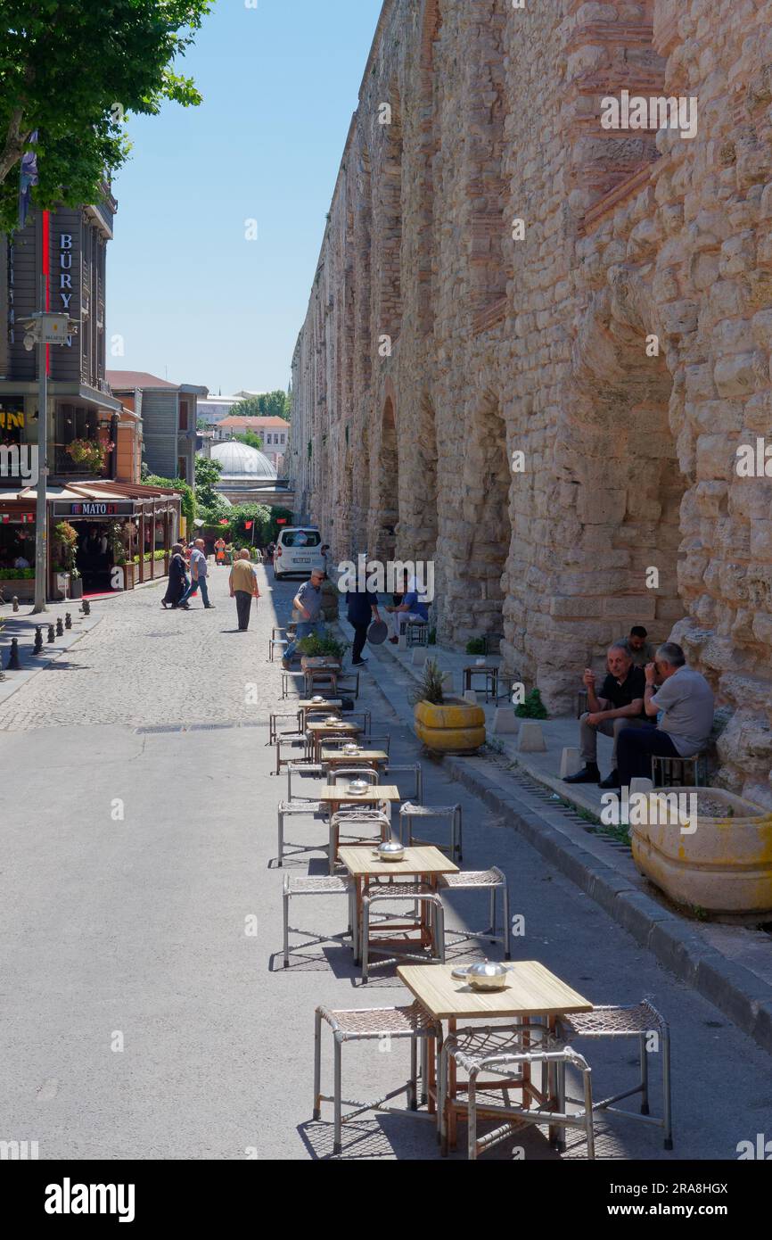 Locals having Turkish Tea on a street beside the Aqueduct of Valens, a Roman Aqueduct in Istanbul, Turkey Stock Photo