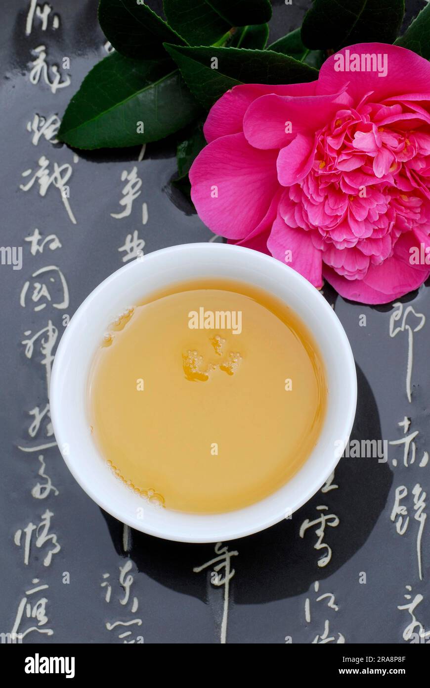 Cup with tea, camellia blossom and japanese characters (Theaceae), camellia Stock Photo
