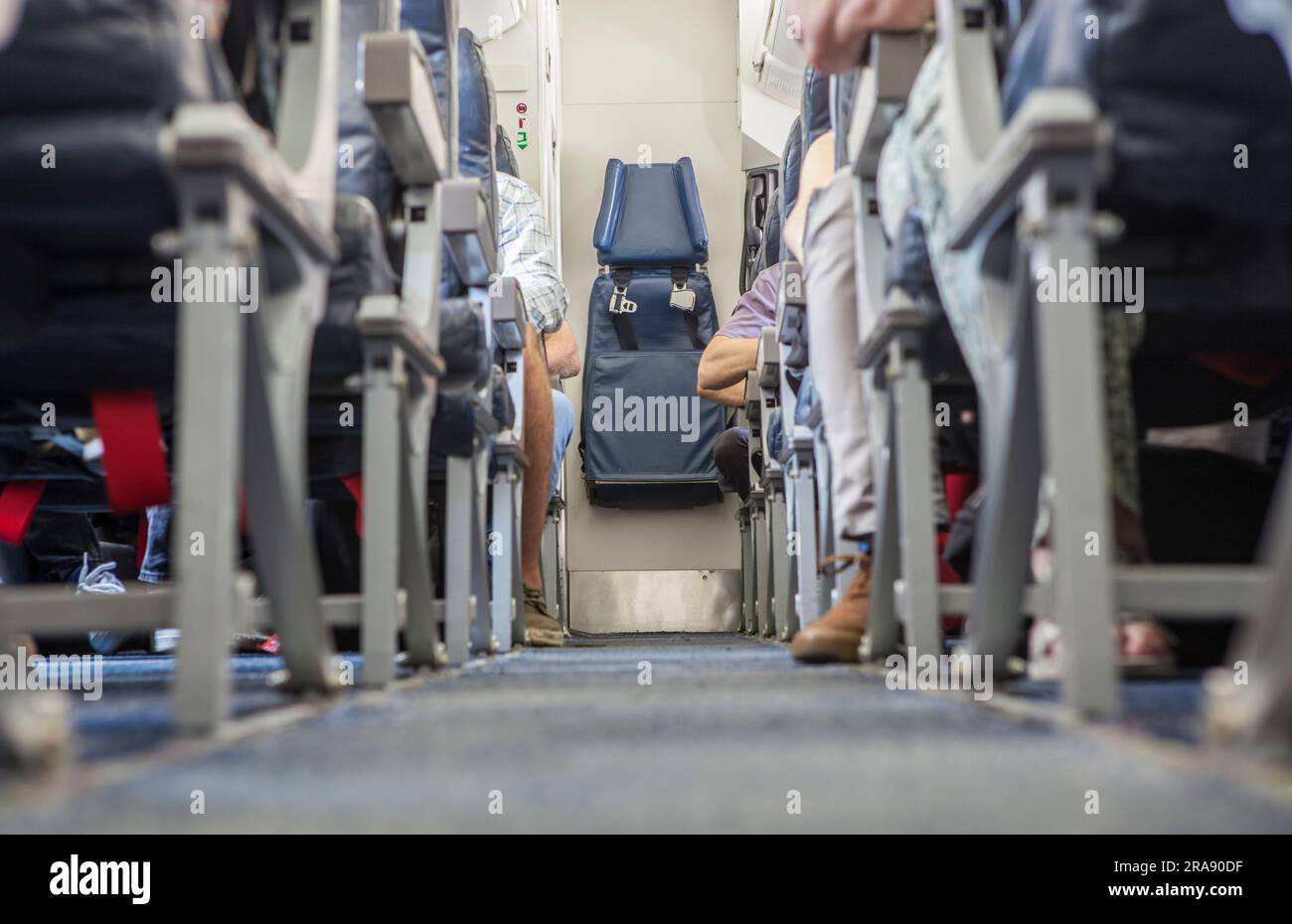 Normal class passenger jet airliner corridor. Tail stewardess seat Stock Photo