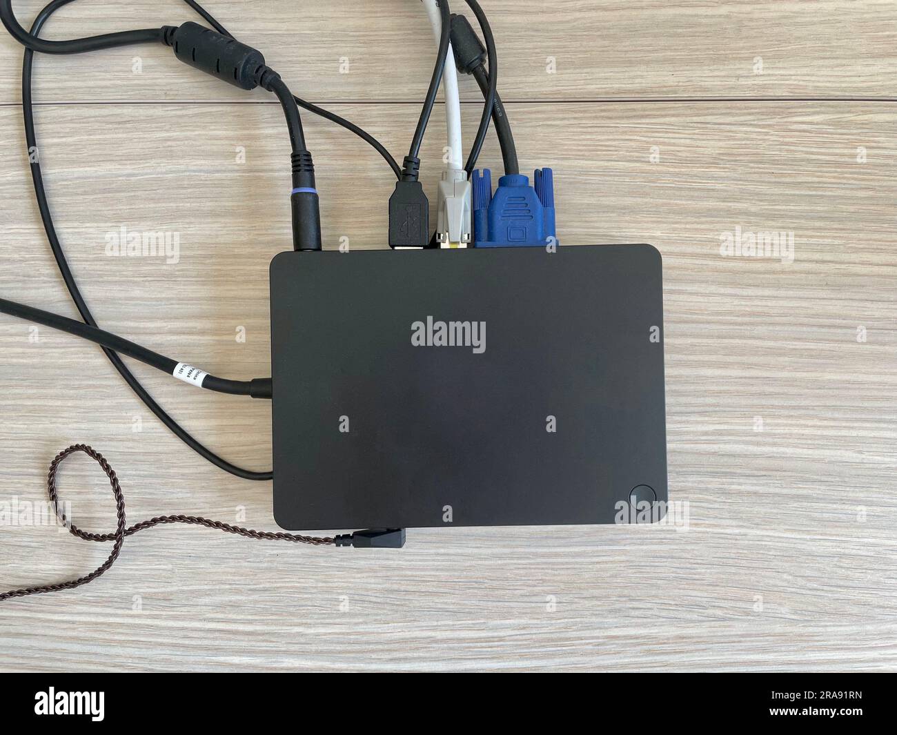 A black docking station with a various cables. Clean office desk and