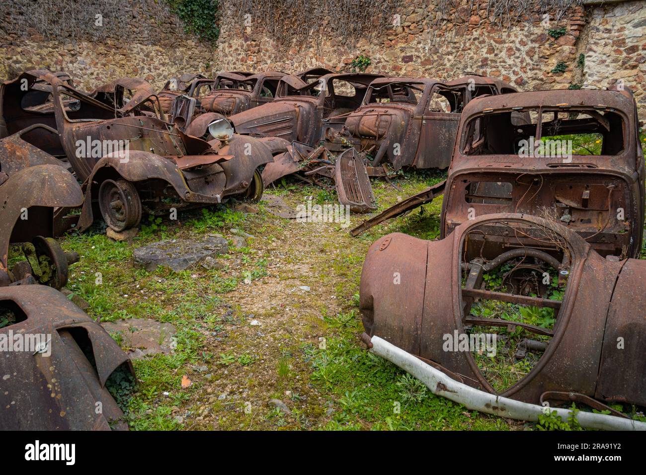 Abandoned scrapyard with old rusty cars in the destroyed village of Oradour sur Glane in France Stock Photo