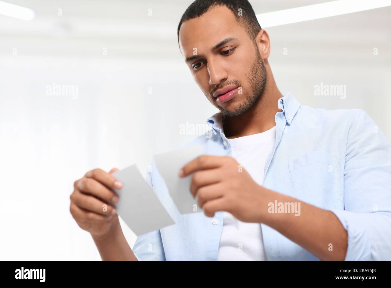 Upset African American man with torn photo indoors Divorce concept Stock Photo