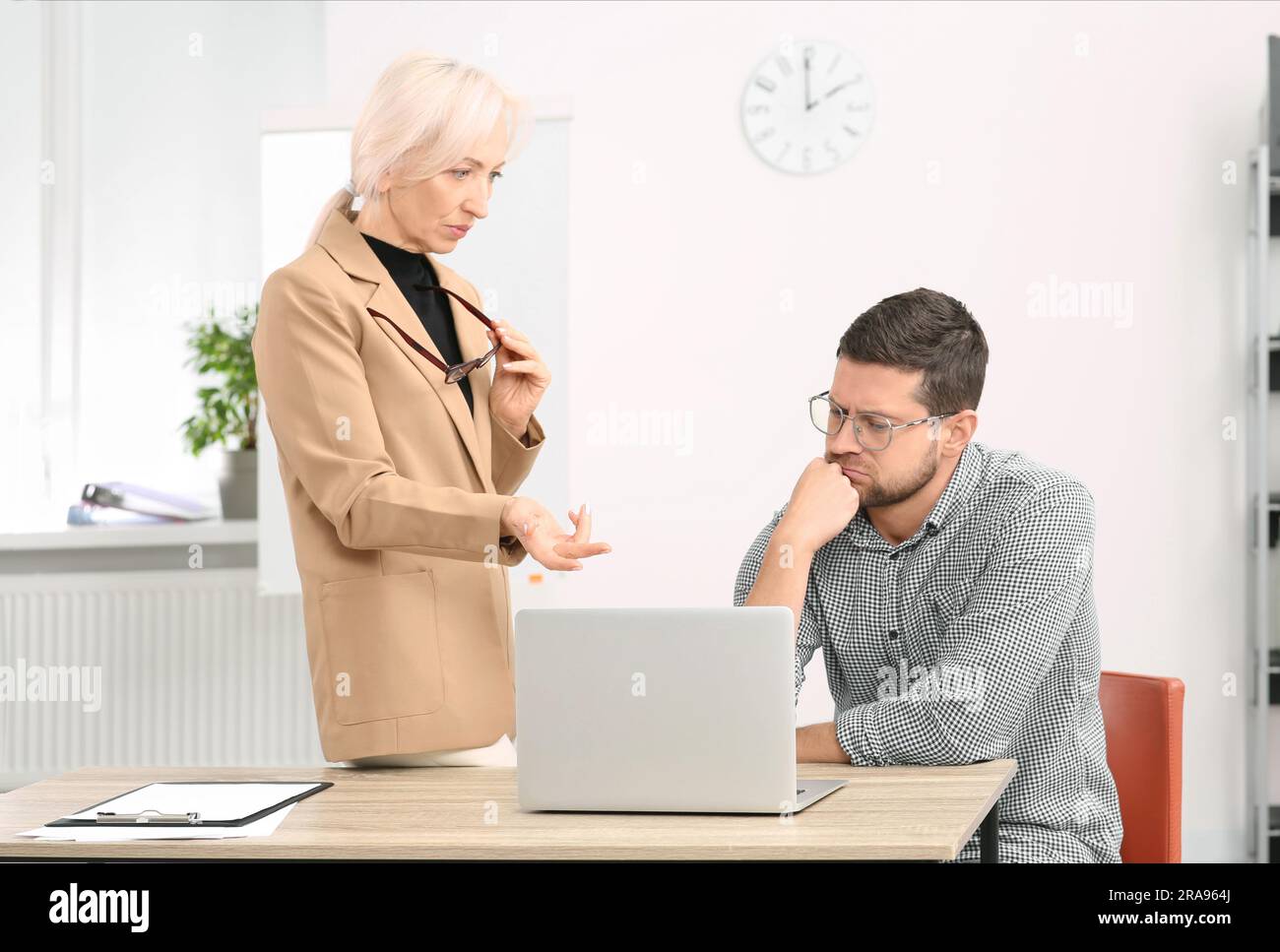 Serious boss and confused employee discussing work issues in office