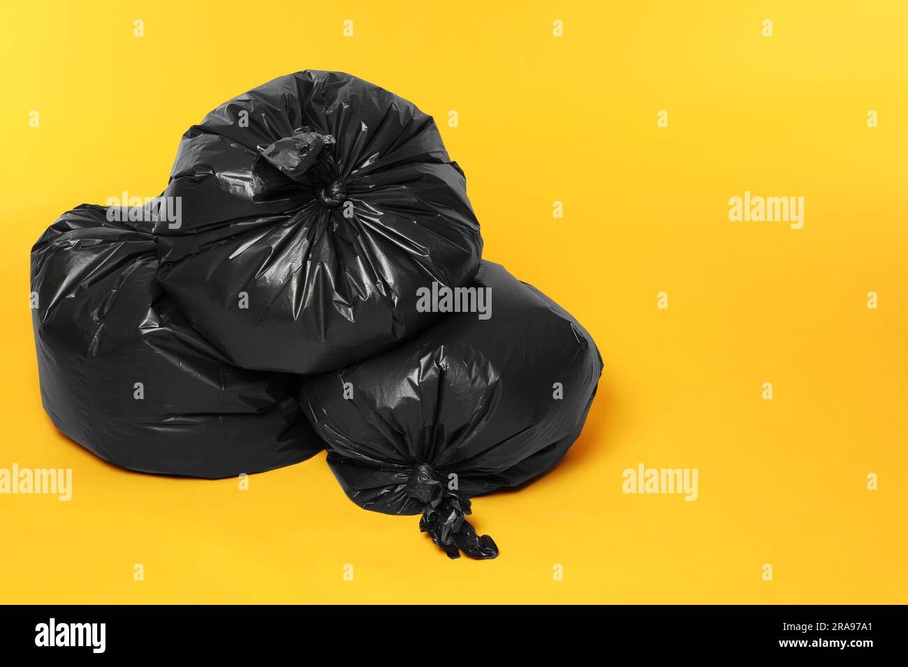 Trash bags full of garbage on orange background. Space for text Stock ...