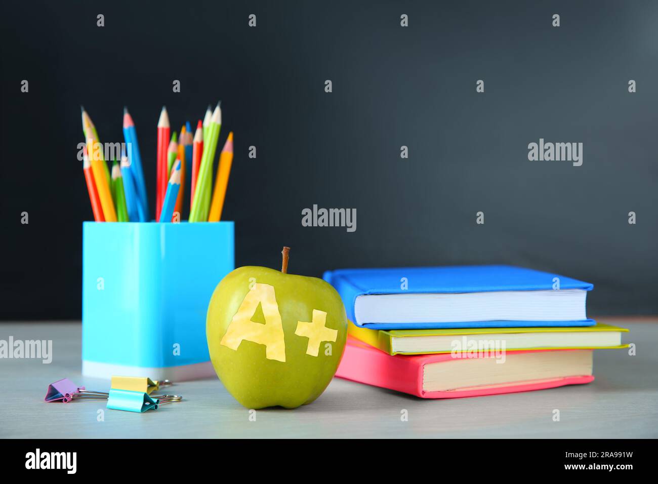 Apple with carved letter A and plus symbol as grade. School stationery on white table in classroom, space for text Stock Photo