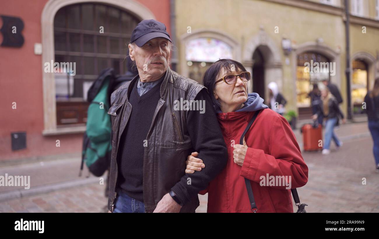 Elderly couple of tourists are walking through the historical center seeing the sights in an old European city. Palace Square, Warsaw Old Town Stock Photo