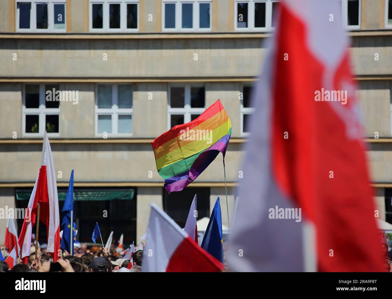 Lots of national flags of Poland an one colourful rainbow colours flag symbolizing LGBTQ+ groups wave during public demonstration to support democracy Stock Photo