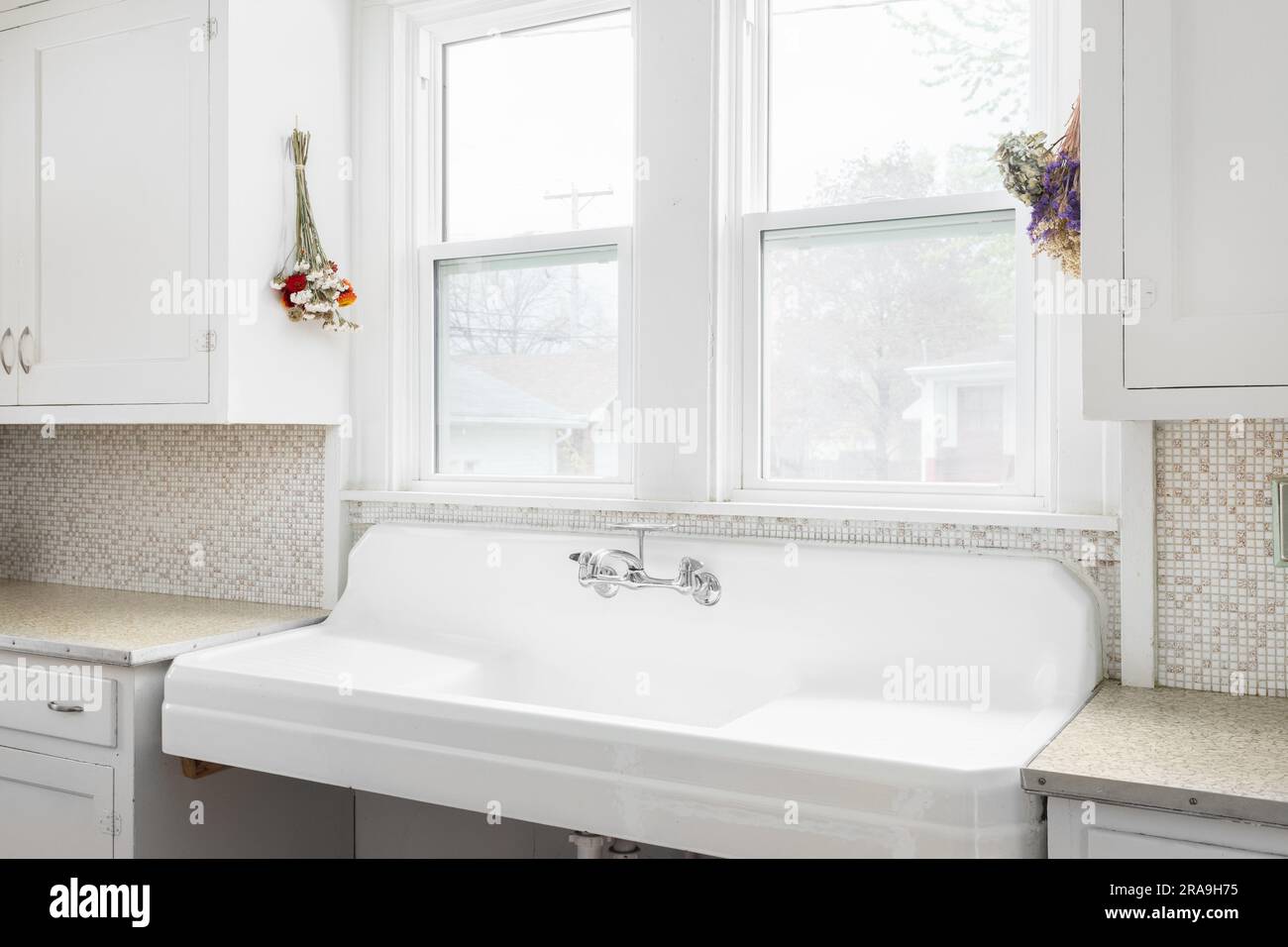 A modern kitchen with charcoal custom cabinets, a marble back splash tile,  and kitchen sink with a chrome faucet in front of a large window Stock  Photo - Alamy