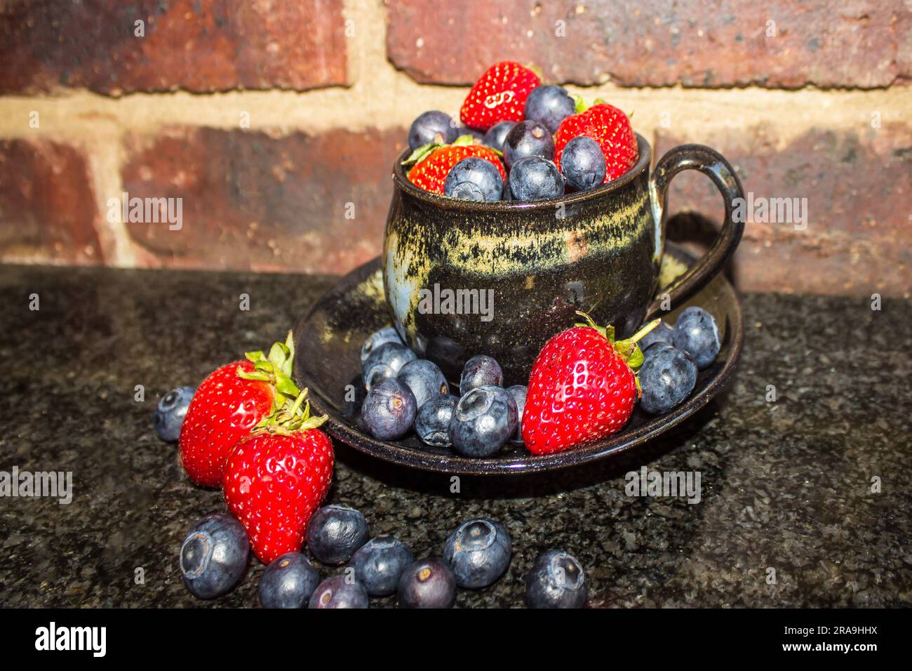 Teacup overflowing with Blueberries and Strawberries Stock Photo