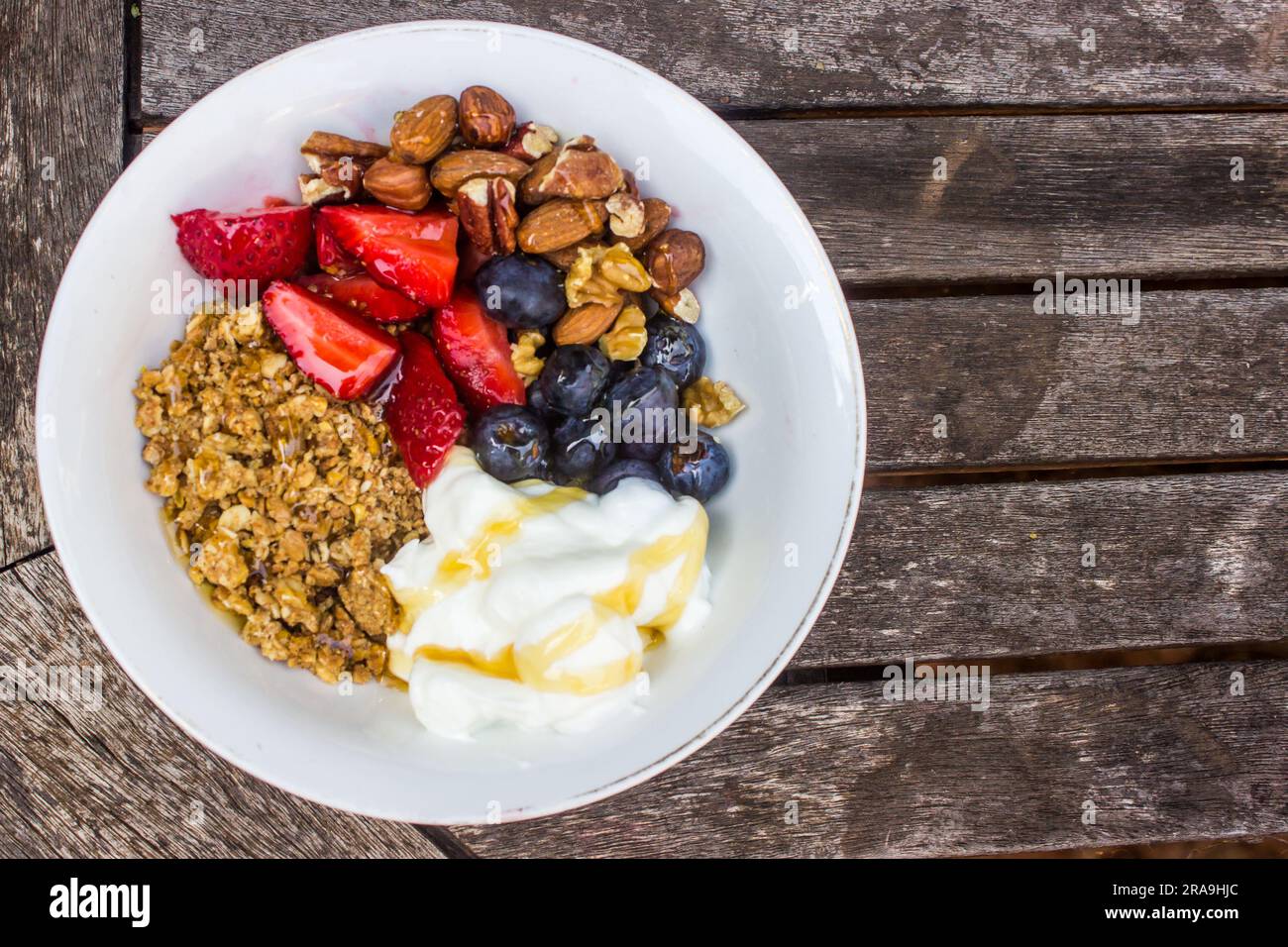 Bowl of Muesli with yogurt and Fresh berries on a rustic weathered wooden table Stock Photo
